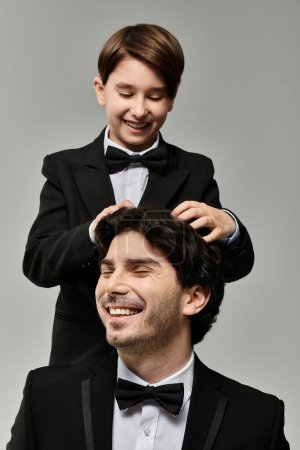 Un padre sonríe contento mientras su hijo juguetonamente se enrosca el pelo.