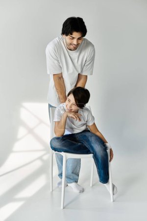 Ein Vater lächelt seinen Sohn an, der auf einem weißen Stuhl sitzt.