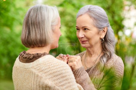 Una pareja de lesbianas se toman de la mano y se sonríen mientras acampan en un exuberante bosque verde.