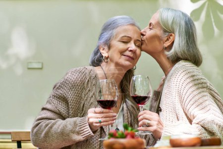 Photo for Two women share a romantic moment while enjoying wine in a forest setting. - Royalty Free Image
