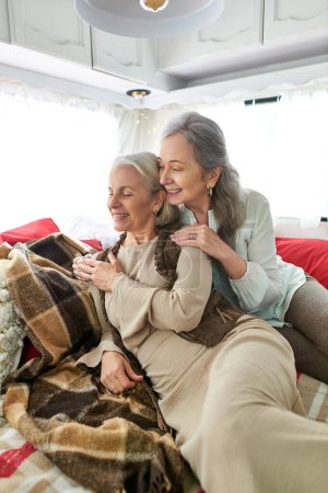 Photo for Two middle-aged women snuggle together in a camper van, enjoying a romantic getaway on the open road. - Royalty Free Image
