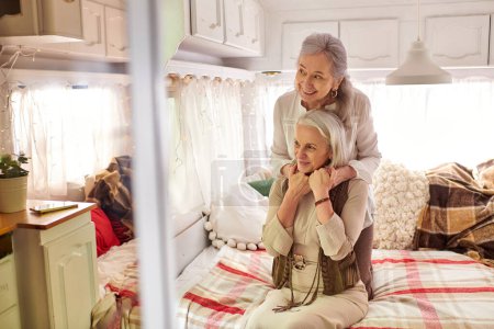 A lesbian couple embraces inside their RV, their faces illuminated with joy and affection.