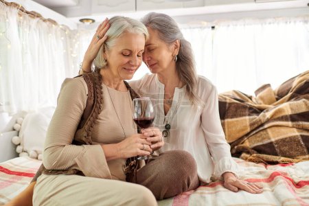 A lesbian couple shares a moment of intimacy and a glass of wine inside their RV.