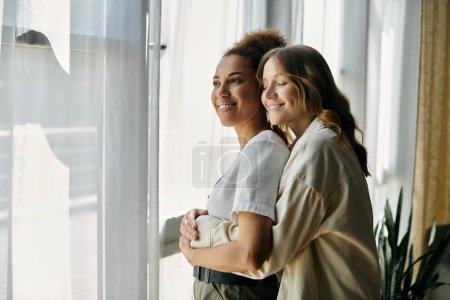 Photo for Two women embracing by a window, enjoying a cozy moment together. - Royalty Free Image
