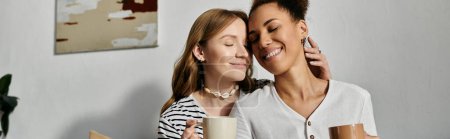 Photo for Two women are cuddling in their home, enjoying a cup of coffee together. - Royalty Free Image