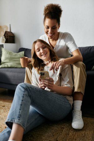 Two women, a lesbian couple, relax at home and look at a phone together.