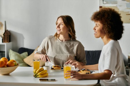 A diverse lesbian couple enjoys a casual breakfast together at home.