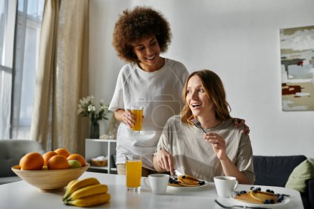 A lesbian couple enjoys a casual breakfast at home.