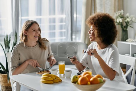 Two women enjoy a casual breakfast together in their home, sharing laughter and a comfortable connection.