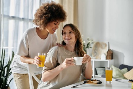 Dos mujeres comparten un momento tierno en casa mientras disfrutan de su desayuno.