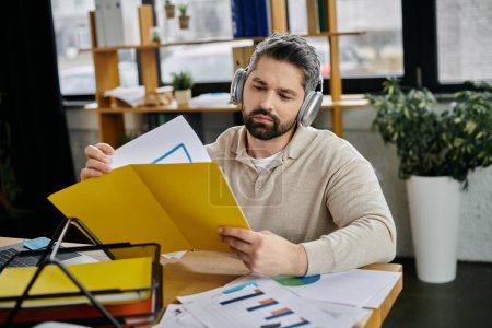 Ein gutaussehender Geschäftsmann mit Bart schaut sich in einem modernen Büro an seinem Schreibtisch Dokumente an.