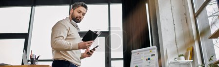 A handsome businessman with a beard works diligently in a modern office setting, reviewing notes and staying connected with his smartphone.