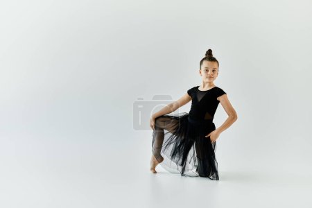A young girl with a prosthetic leg performs a gymnastic pose in a studio.