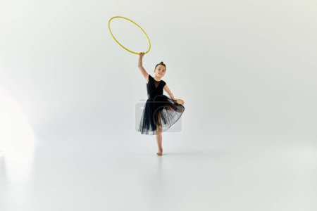 A young girl with a prosthetic leg practices gymnastics with a hula hoop in a studio.
