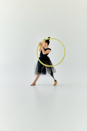 A young girl with a prosthetic leg performs gymnastics with a hula hoop.