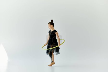 A young girl with a prosthetic leg performs a gymnastics routine with a hula hoop.