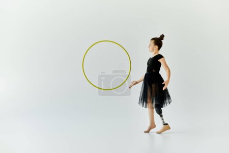 A young girl with a prosthetic leg practices gymnastics with a hoop in a studio.