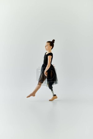 Une jeune fille avec une jambe prothétique fait un pas gracieux dans un studio de ballet.