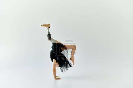 A young girl with a prosthetic leg performs a handstand during a gymnastics routine.