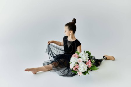 A young girl with a prosthetic leg performs a gymnastics split while holding a bouquet of flowers.