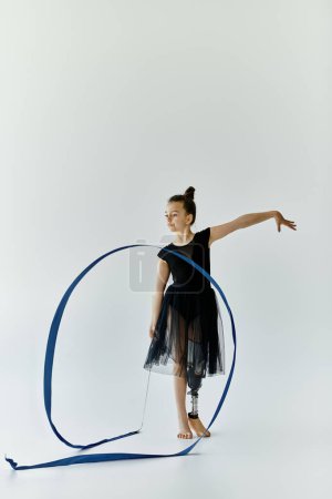 A young girl with a prosthetic leg performs a graceful gymnastics routine with a ribbon.