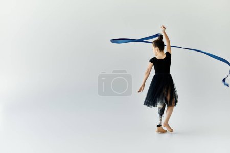 A young girl with a prosthetic leg gracefully performs a ribbon routine.