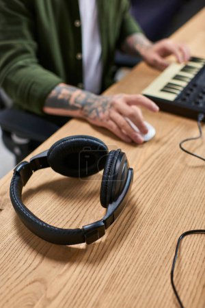 A pair of black headphones lay on a wooden table in a recording studio.