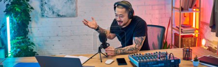 Photo for A young Asian man records a podcast in his home studio. - Royalty Free Image