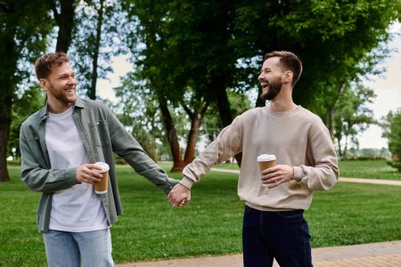 A happy gay couple walks hand-in-hand through a green park, laughing and enjoying their time together.