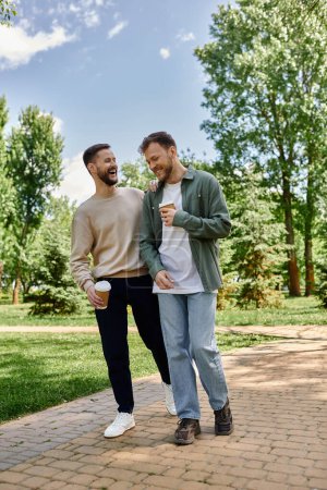 A bearded gay couple walks hand-in-hand through a lush green park, laughing and enjoying each others company.
