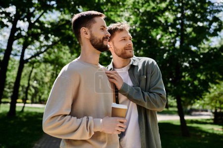 A gay couple with beards enjoy a coffee break in a green park, sharing a moment of love and intimacy.