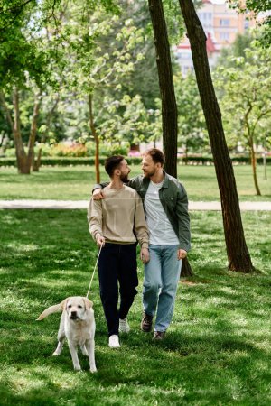 Two bearded men, a gay couple, casually dressed, walk together with their labrador in a lush green park.