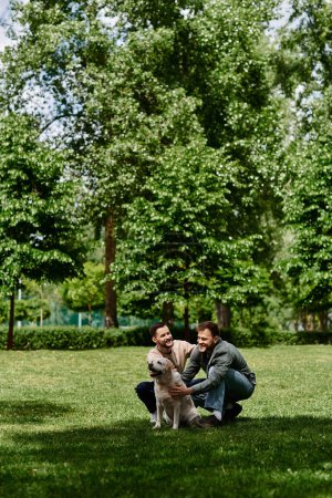Dos hombres gays barbudos con ropa casual disfrutan de un día soleado en un parque verde con su labrador retriever.