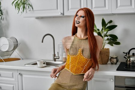 A glamorous drag queen poses in a kitchen, showcasing her stylish attire.