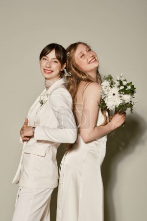 A lesbian couple, dressed in white attire, smiles for a photo on their wedding day.