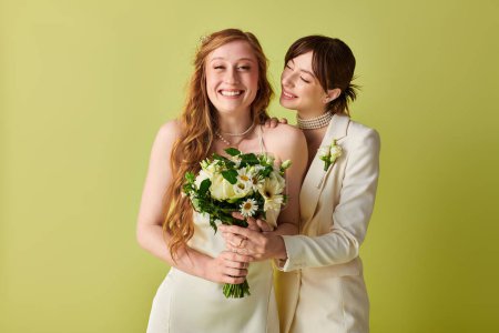 Two brides, dressed in white, share a joyous moment on their wedding day. The bride on the left holds a bouquet of white flowers, while the bride on the right has her arm around her partner.