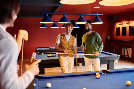 Friends play billiards in a dimly lit room, enjoying a relaxed evening together.