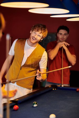 Friends enjoy a casual game of billiards under the warm glow of the pub lights.