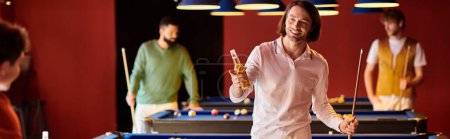 Un grupo de amigos juega al billar en una habitación con poca luz, disfrutando de bebidas y buena compañía.