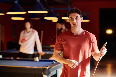 A group of friends enjoy a casual night of billiards in a dimly lit, stylish setting.