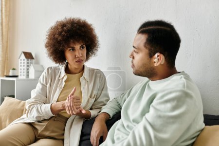 Ein afroamerikanisches Paar sitzt auf einer Couch und führt ein herzliches Gespräch mit Gebärdensprache.
