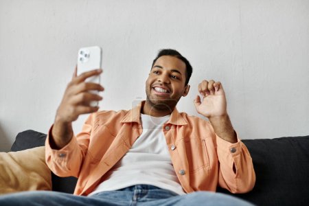A smiling man uses sign language while video chatting on his phone.