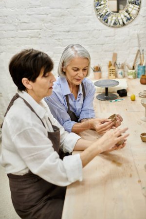 Two women are working together on pottery in an art studio.
