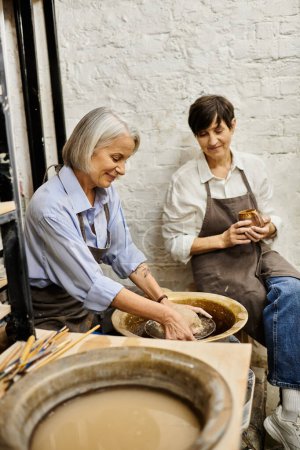 Two women craft together in a pottery studio, enjoying a shared creative moment.