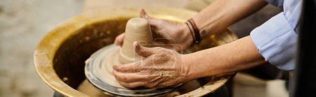 Une main de femme forme de l'argile sur une roue de poterie.