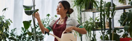 Une jeune femme asiatique portant un tablier a tendance à planter dans son magasin de plantes.