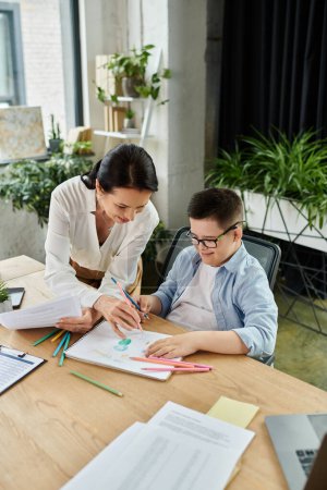 A mother and son with Down syndrome are drawing together in a modern office, showcasing inclusivity and diversity in the workplace.