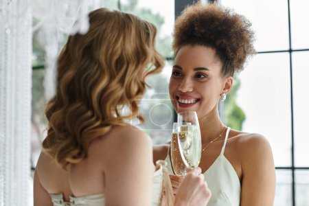 Two brides raise a glass of champagne to celebrate their love on their wedding day.