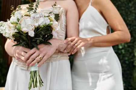 A lesbian couple hold hands and share a loving moment on their wedding day.