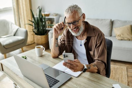 A mature gay man with grey hair and tattoos works remotely from home.